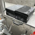 Pile d'ardoises plates noires disposées sur un élévateur