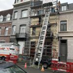 Echafaudage, élévateur, barrières et camionnette devant la façade d'une maison de rangée