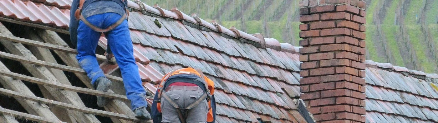 Ouvriers équipés de harnais de sécurité sur une toiture en rénovation